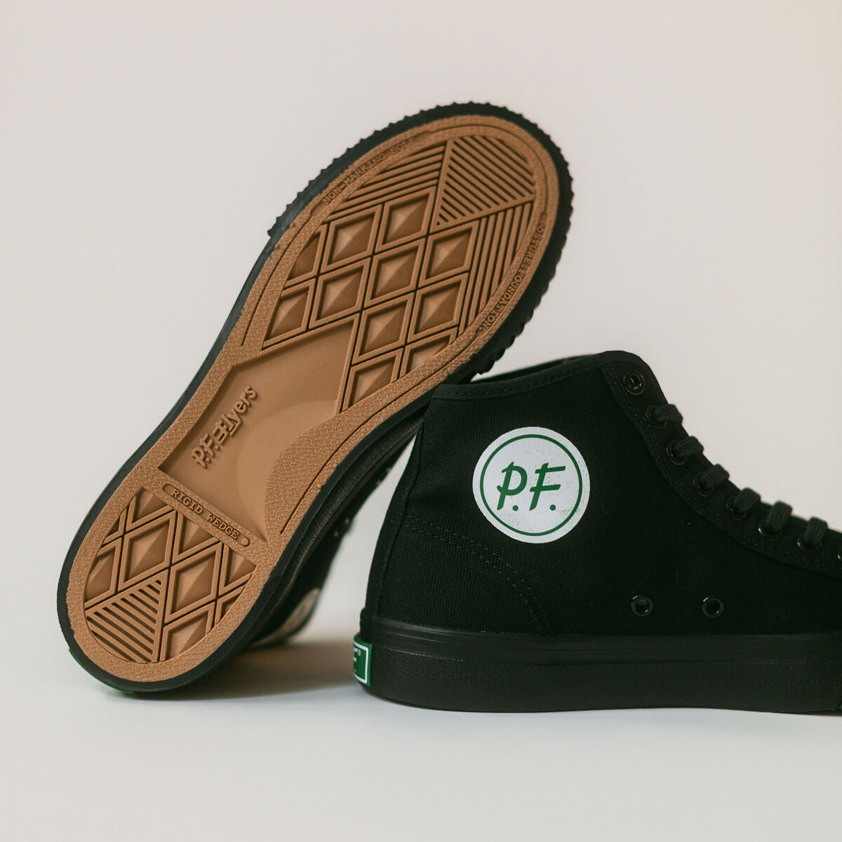 Black high-top sneakers with the green P.F Flyers logo on a light gray background