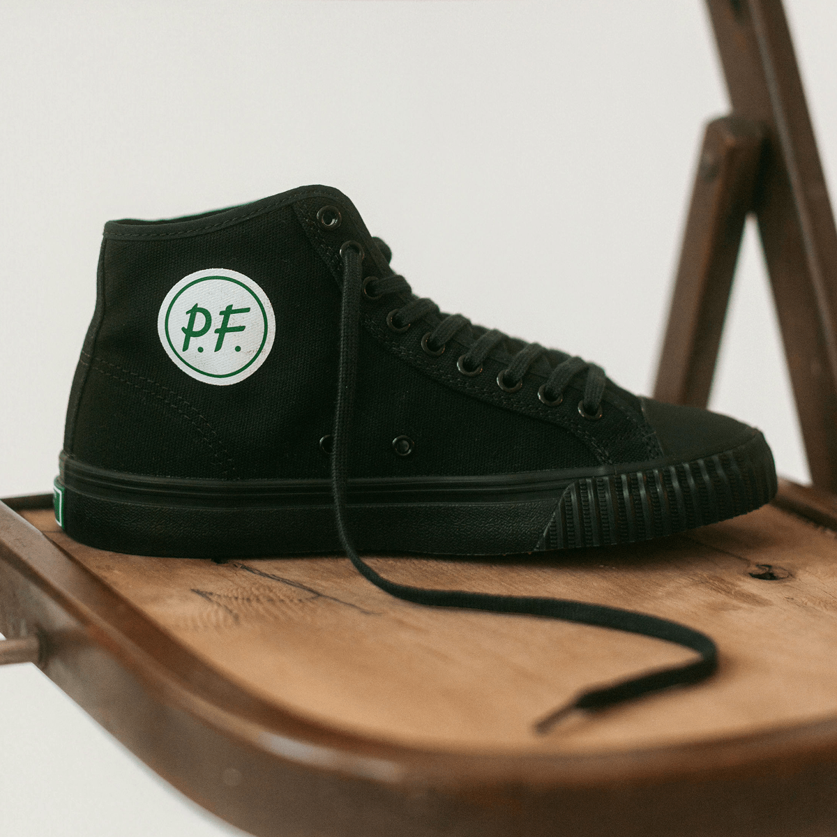 Close up of a black high-top sneaker on a wooden chair.