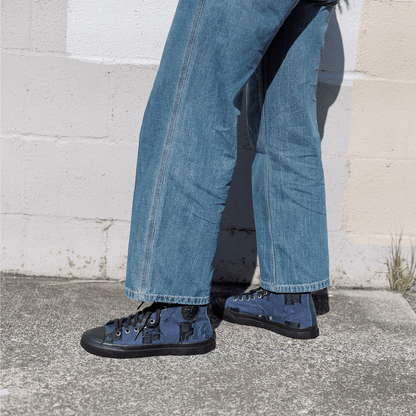 Person wearing blue jeans and matching sneakers standing on a concrete surface with a light-colored wall in the background.