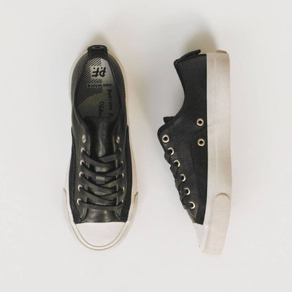 Black sneakers with white soles on a light gray background