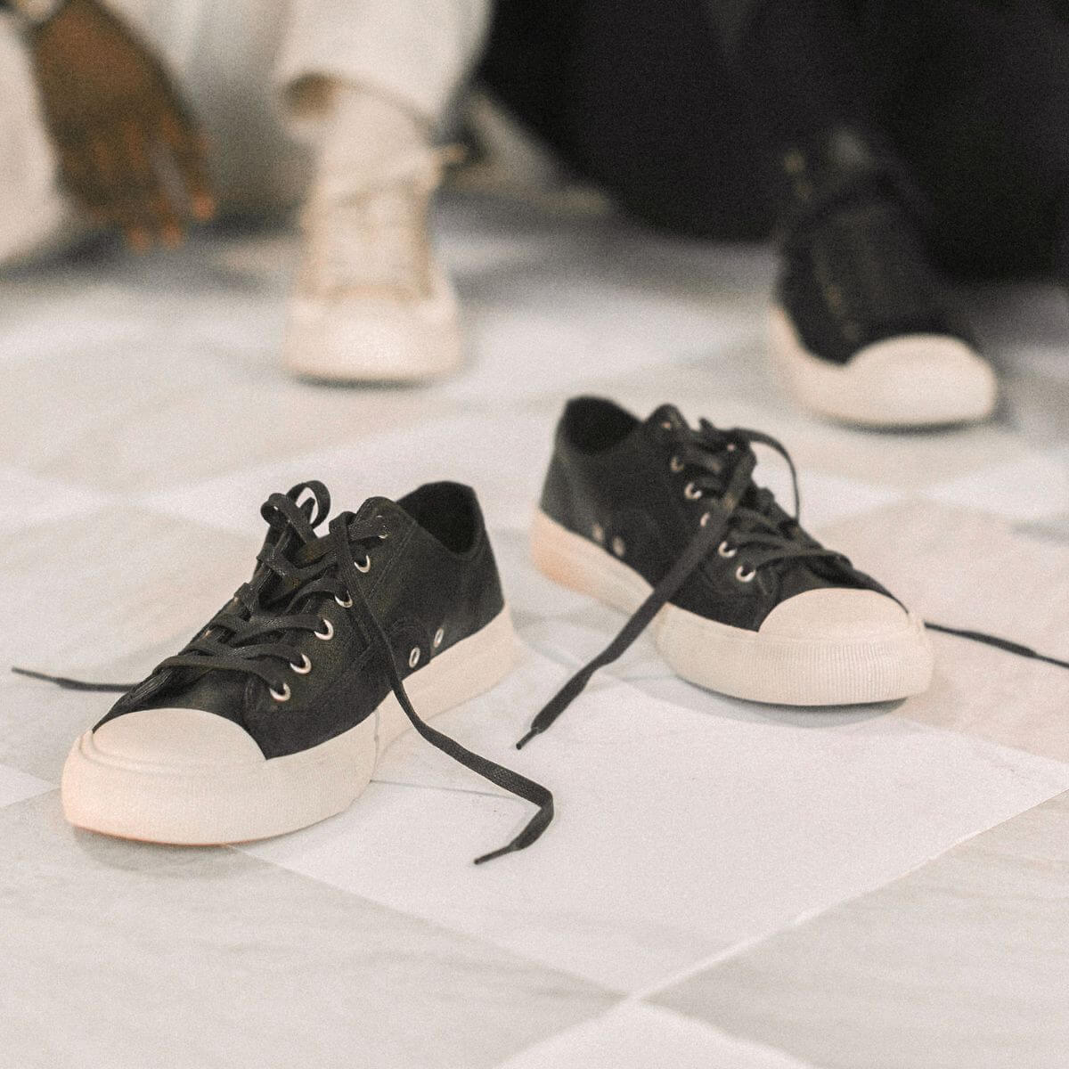 Black sneakers with white soles on a checkered floor