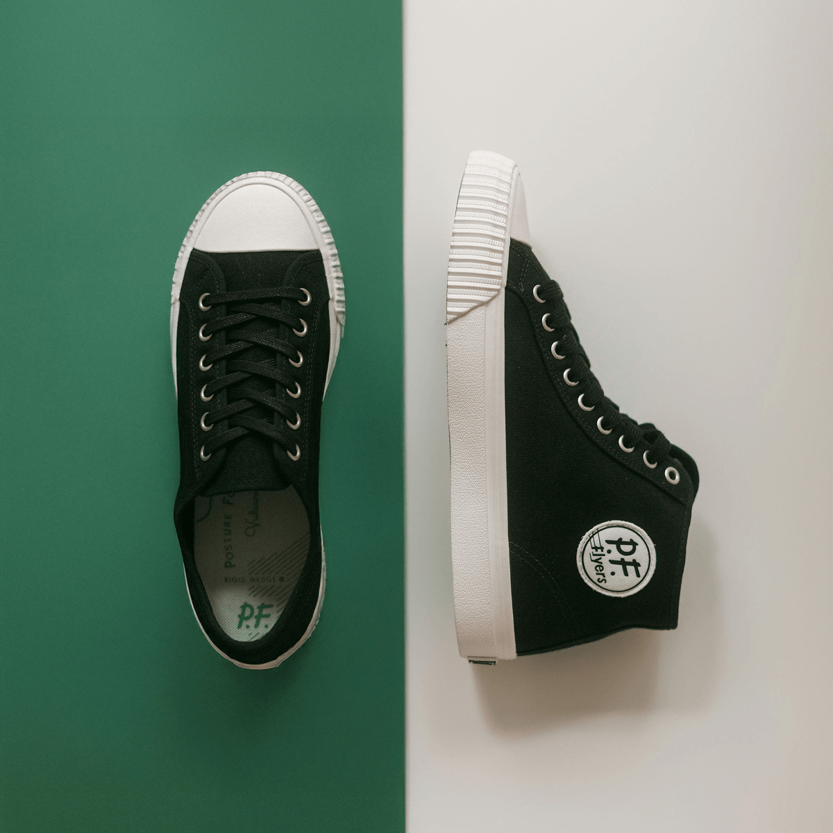 Black high-top sneakers with white soles on a green and white background.