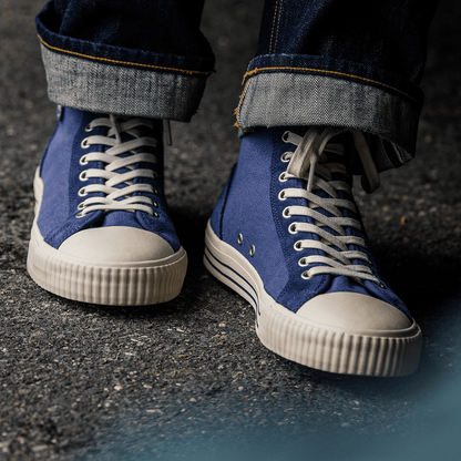 Blue high-top sneakers with white soles on a concrete surface.