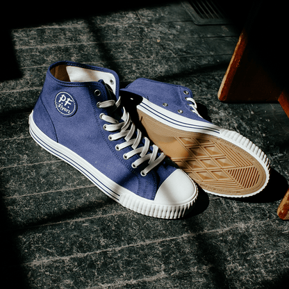 Blue high-top sneakers with white soles illuminated by natural light.