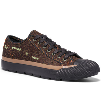 Brown low-top sneaker on a white background, with “Stay grounded in nature” embroidered on the upper.