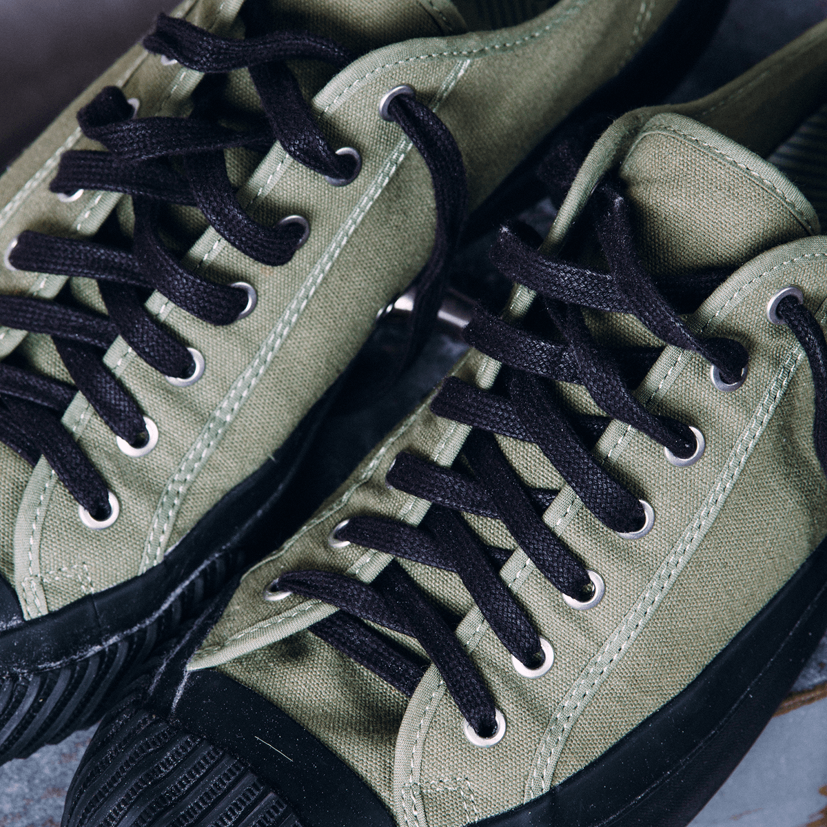 Close-up of olive green low-top sneakers with black laces.