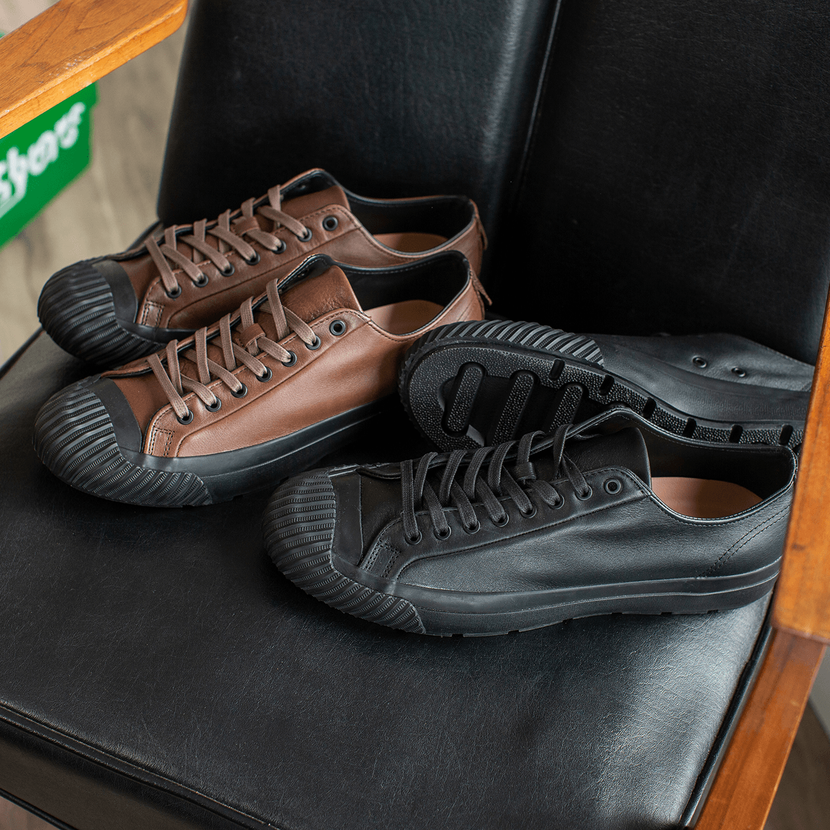 Pair of brown and black leather low-top sneakers on a chair.