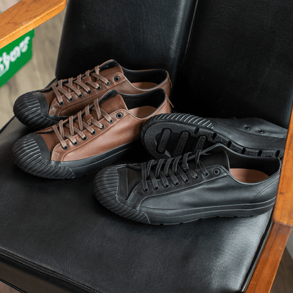 Pair of brown and black leather low-top sneakers on a chair.