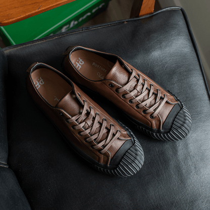 Brown leather low-top sneakers on a chair.