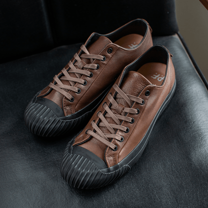 Brown leather low-top sneakers on a chair.