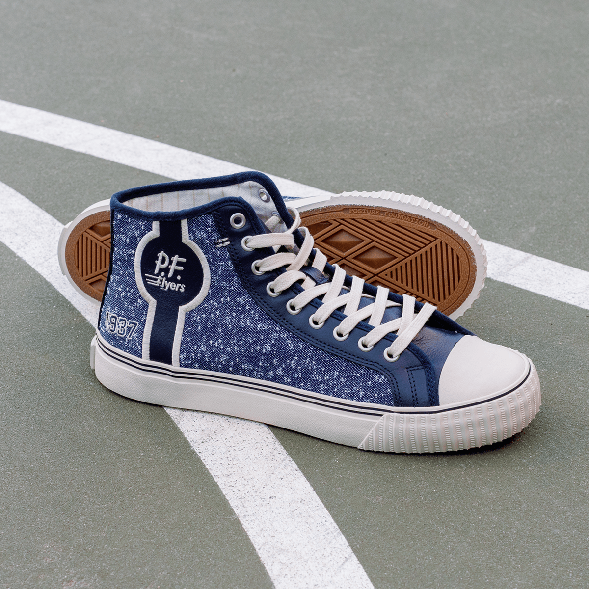 Navy high-top sneakers with white soles on a court.
