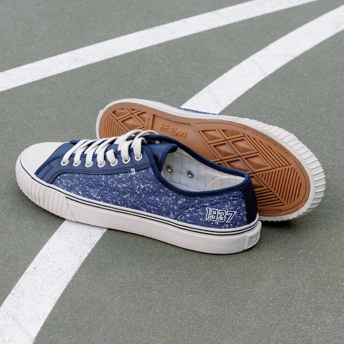 Navy low-top sneakers with white soles on a court.