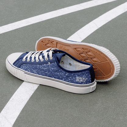 Navy low-top sneakers with white soles on a court.