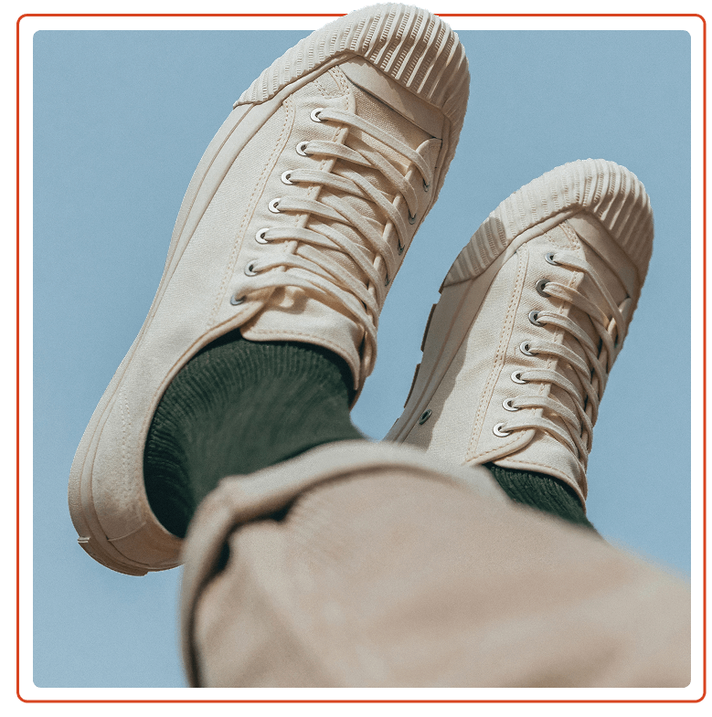 Closeup of off-white sneakers against a clear blue sky.