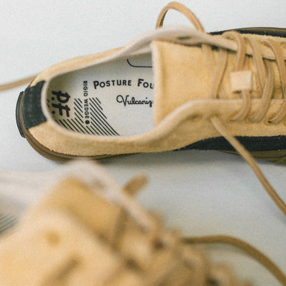 Close-up of a tan shoe with visible P.F. branding on a light background