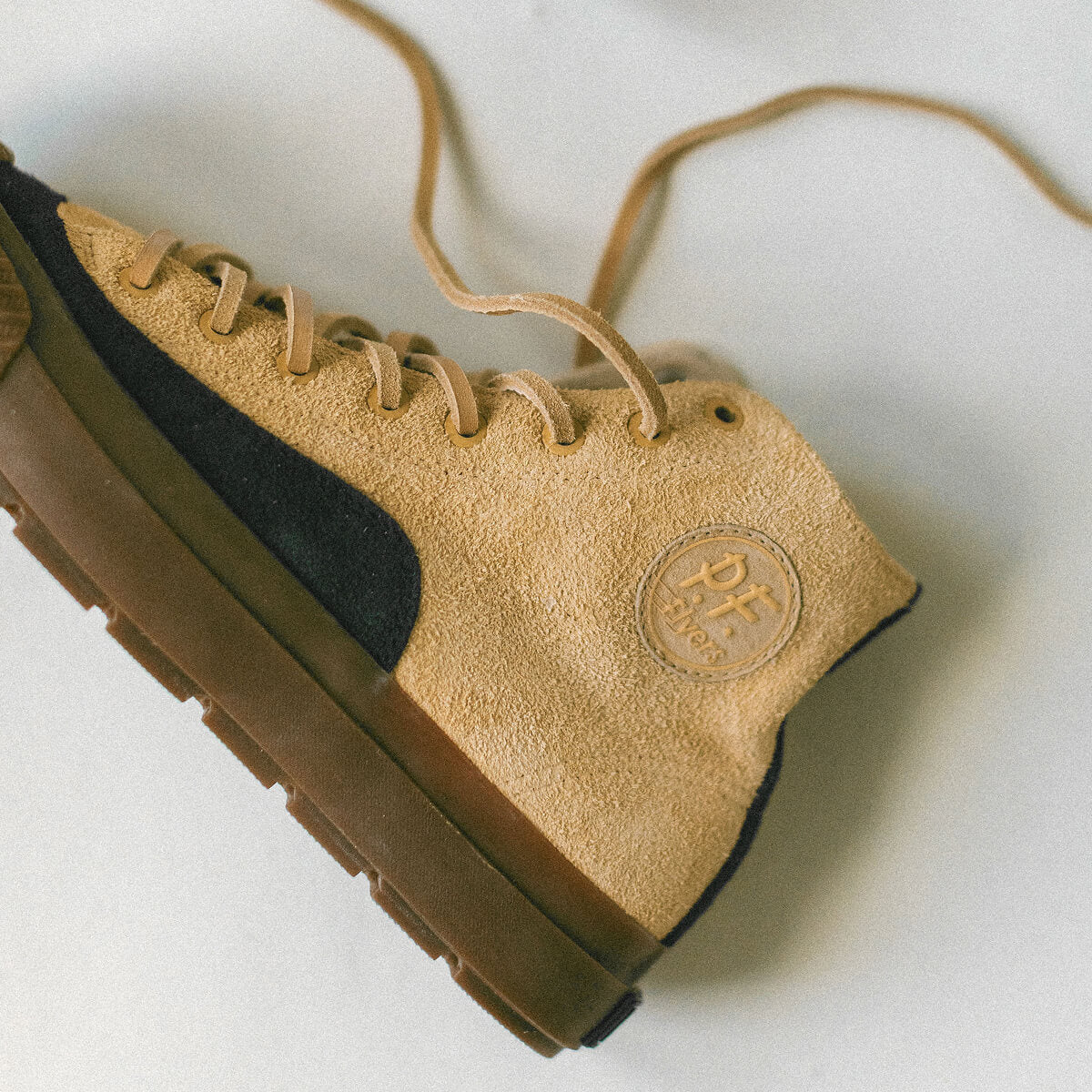 Tan and black sneaker with a P.F. Flyers logo on a light background