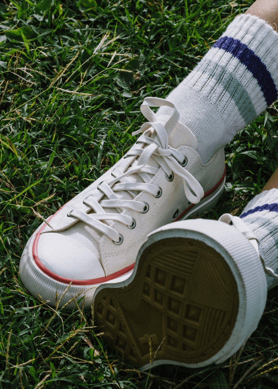 White sneakers with brown soles on grass